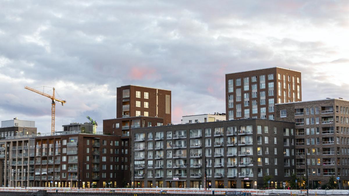 Nya höghus och en byggarbetsplats med en tornkran i stadslandskapet i kvällsljus.