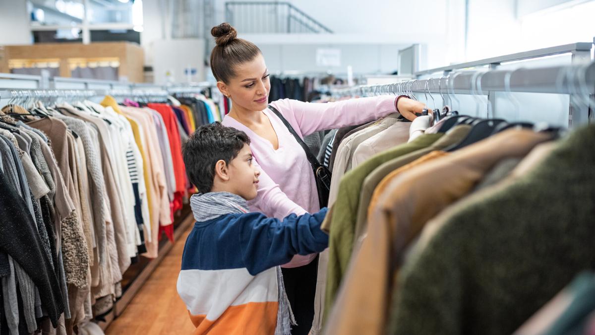A woman and a boy are shopping clothes in the Reuse Centre.