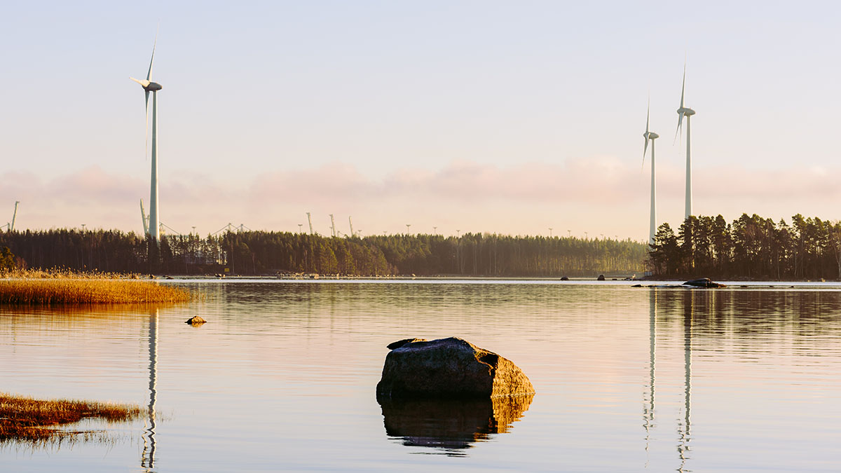 Maisemakuva merenrannalta, jossa taustalla tuulimyllyjä.