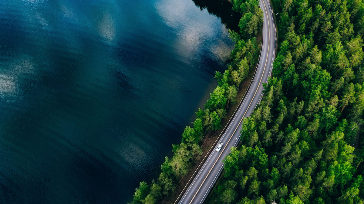 Ilmakuva, jossa näkyy järvi, metsää ja tie