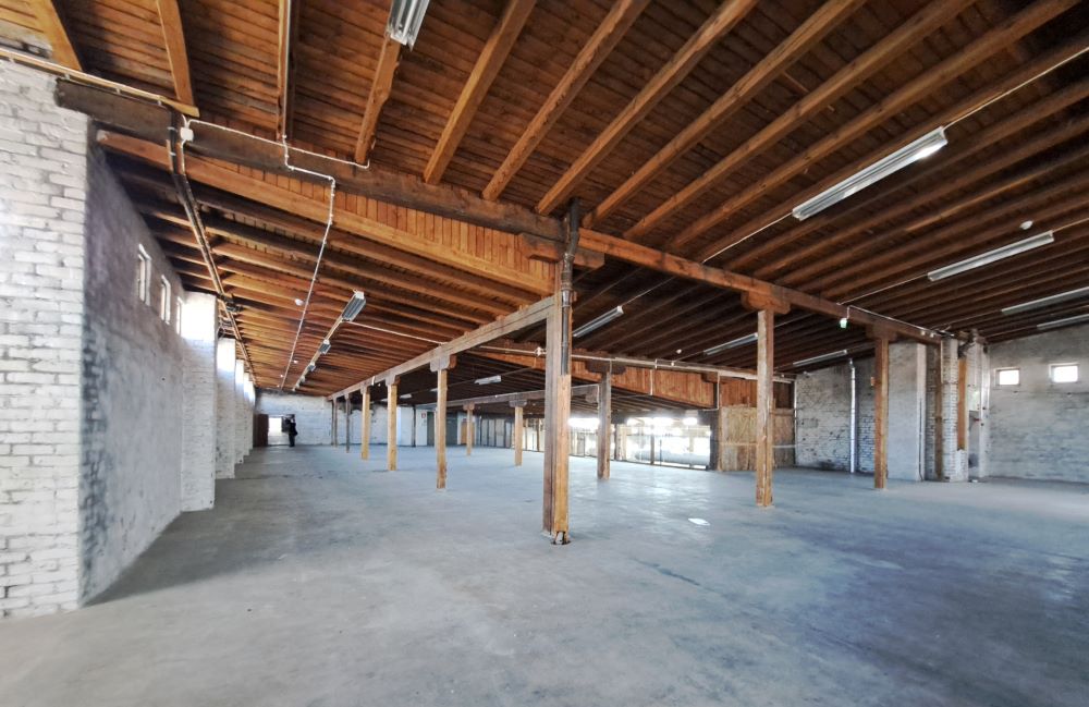 Kuvituskuvassa iso avonainen tila vanhassa rakennuksessa. Tilassa valkoiset tiiliseinät ja puukatto.