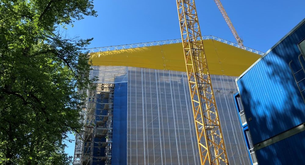 Kuvituskuvassa rakennustyömaalla rakennus suojattuna sääsuojateltalla.